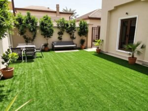 حديقة منزلية جميلة مغطاة بالعشب الصناعي مع أثاث خارجي